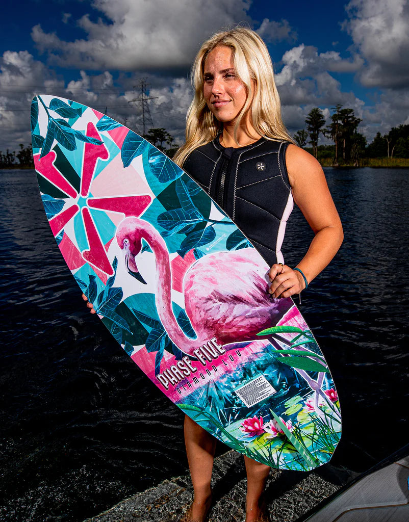 A woman holding a Phase 5 2024 Diamond Luv Wakesurf Board with a flamingo on it.