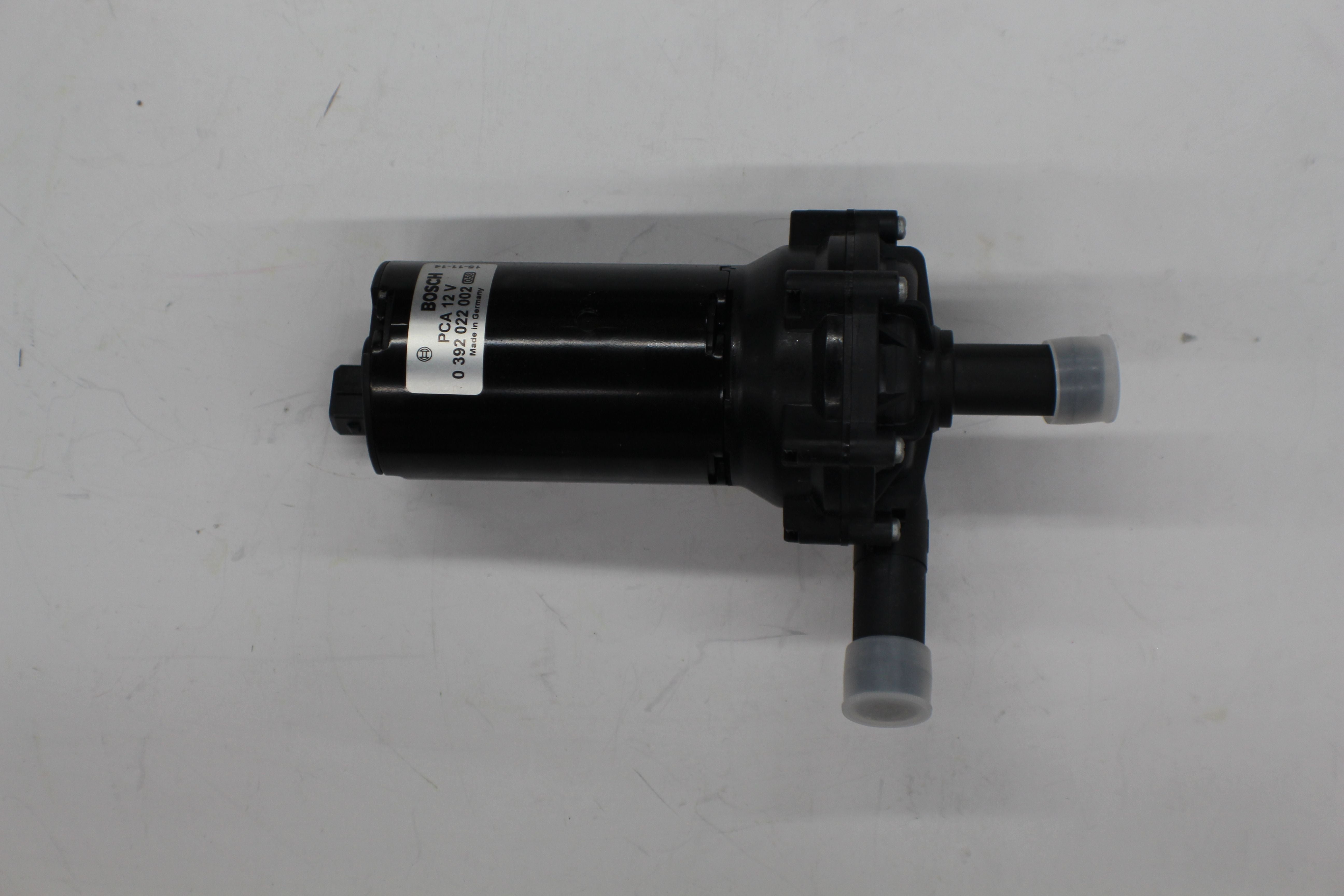 The Indmar PUMP ASM FORD 6.2L INTERCOOLER - 687002 is a black cylindrical pump with two nozzles capped with translucent covers and a small side extension, designed for automotive use, shown on a plain white background. Brand: Indmar.