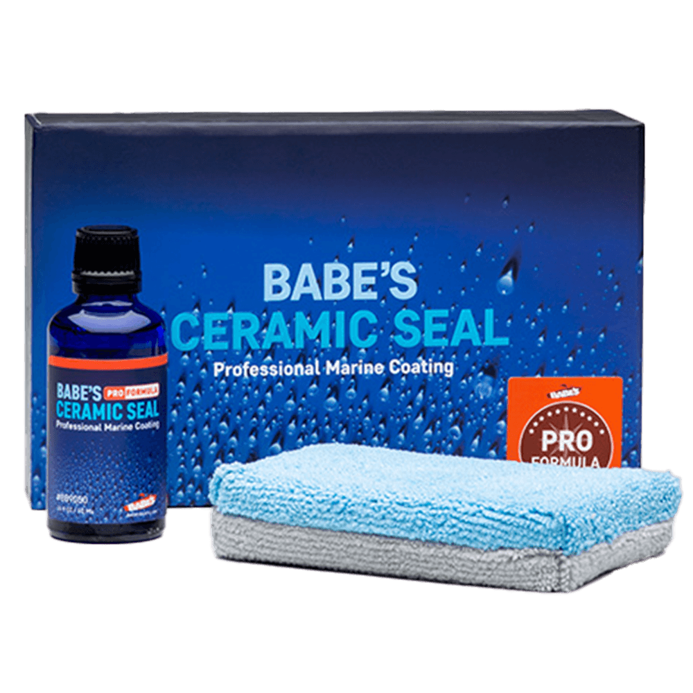 A blue bottle labeled BABE'S Ceramic Seal – Pro Formula from BABE'S Boat Care sits before a blue box reading "BABE'S Ceramic Seal Professional Marine Coating" and beside a folded blue-and-gray microfiber cloth.