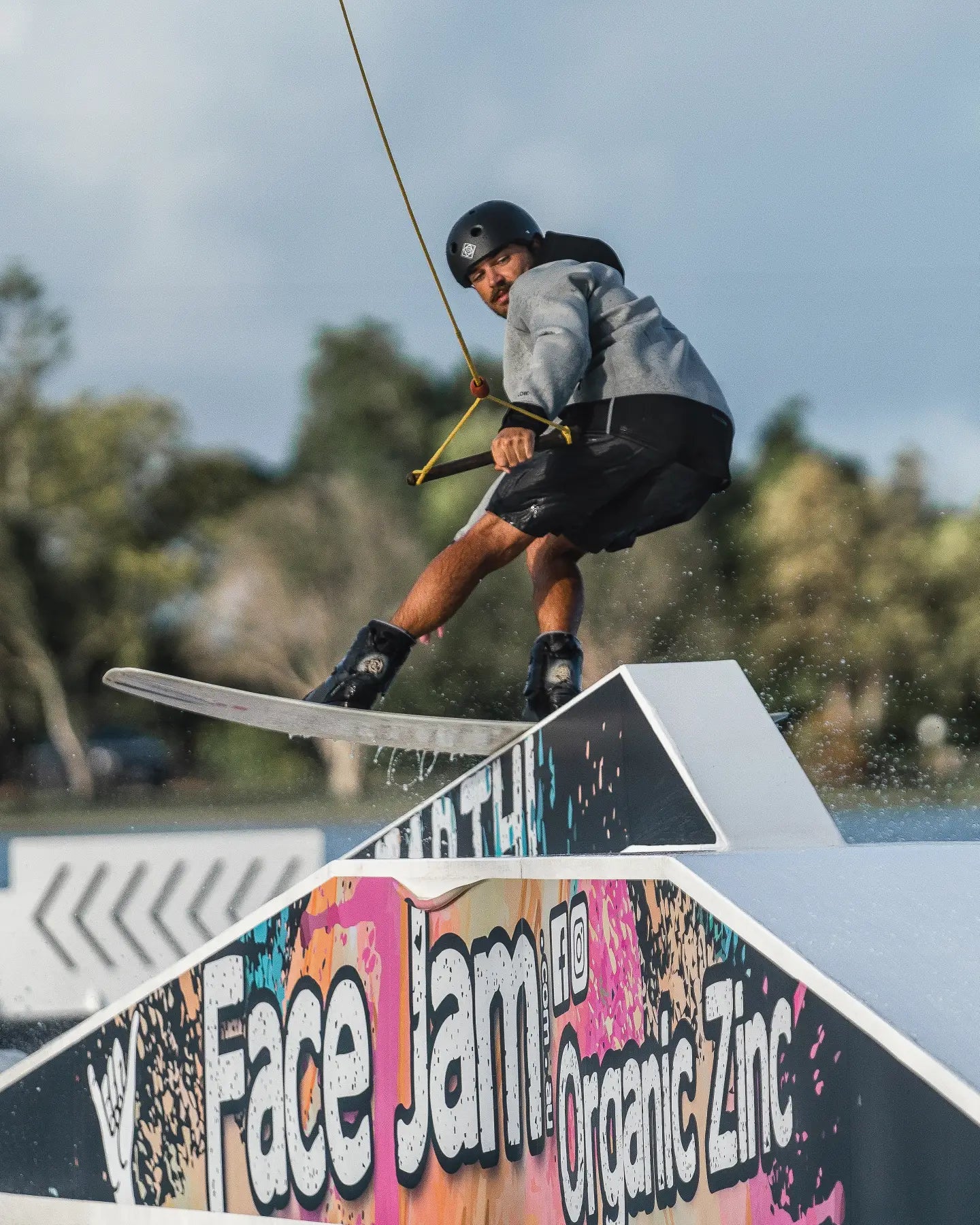 Alex Aulbach does a trick on his wakeboard wearing the Follow Pro Neo Jacket in Cream