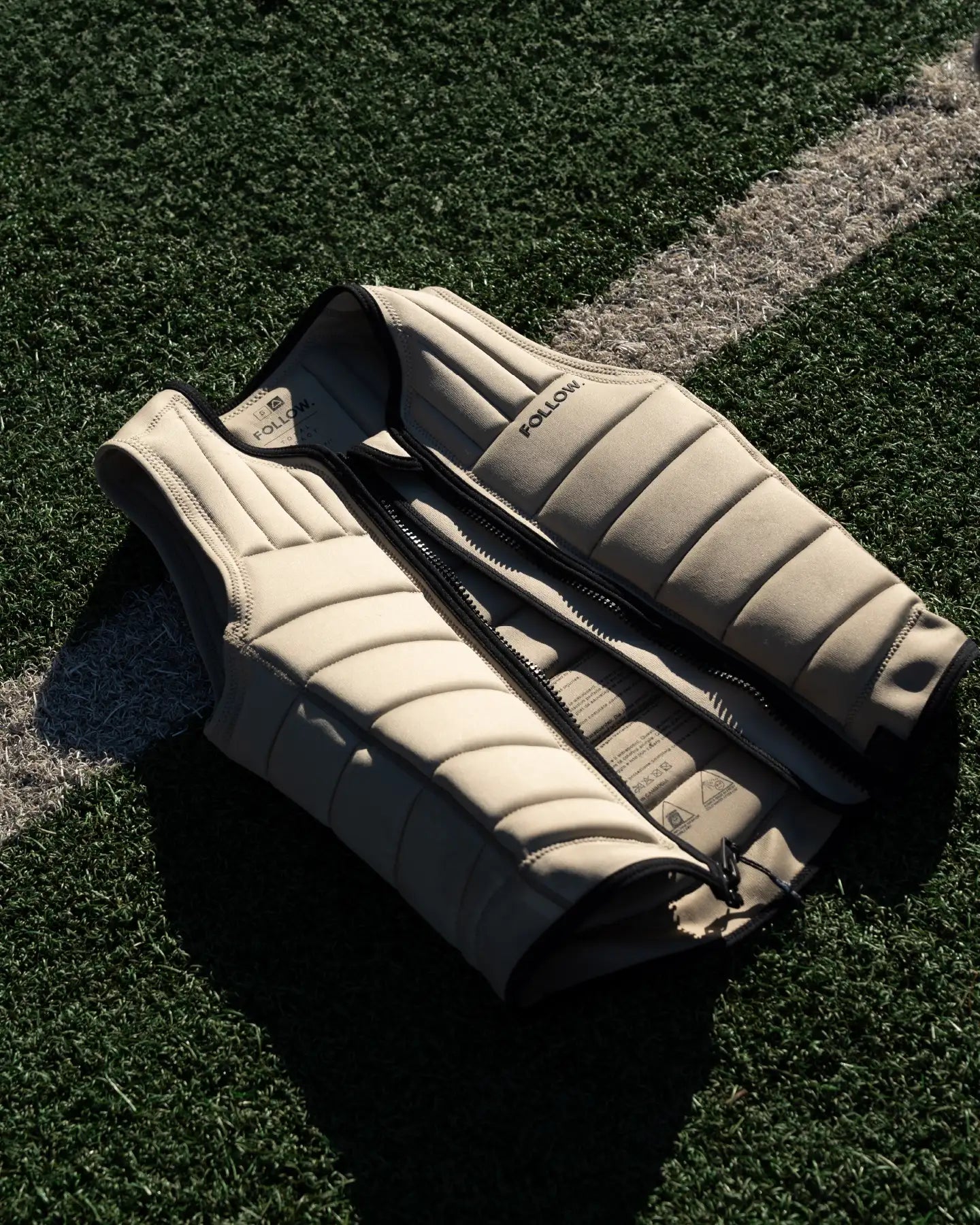 Follow Total Men's Impact Vest - Sand laid on a football field