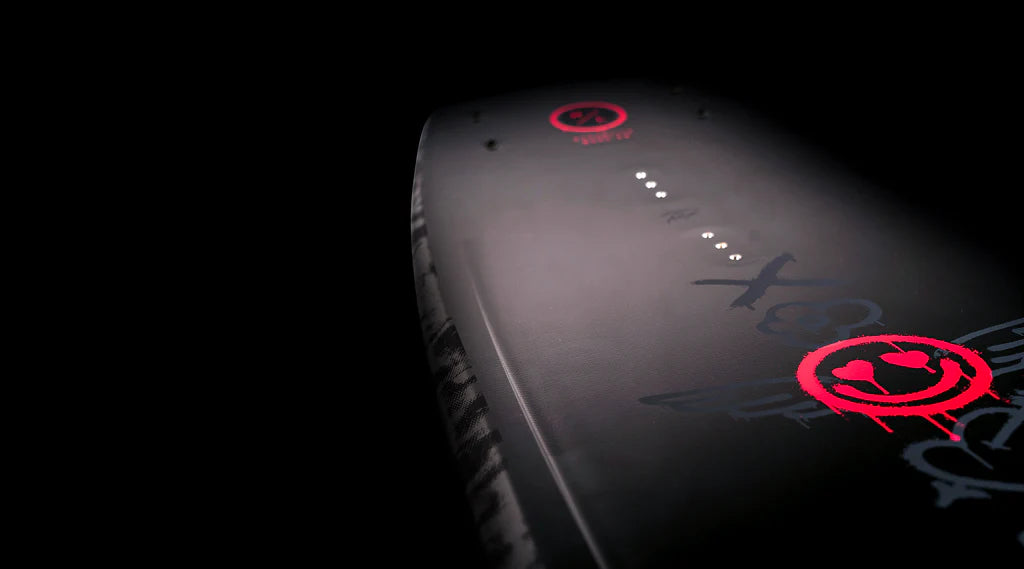 Close-up of the Hyperlite 2025 Journey Wakeboard, featuring red graphic designs and text on its dark surface, highlighting the Biolite 3 Core construction against a black background.