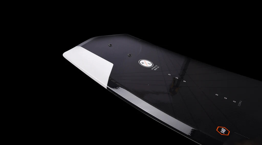 Close-up of the Hyperlite 2025 State Jr Wakeboard with Remix Bindings, featuring a black carbon fiber design with a white edge against a black background, highlighting its asymmetrical shape that enhances toe-side transitions.