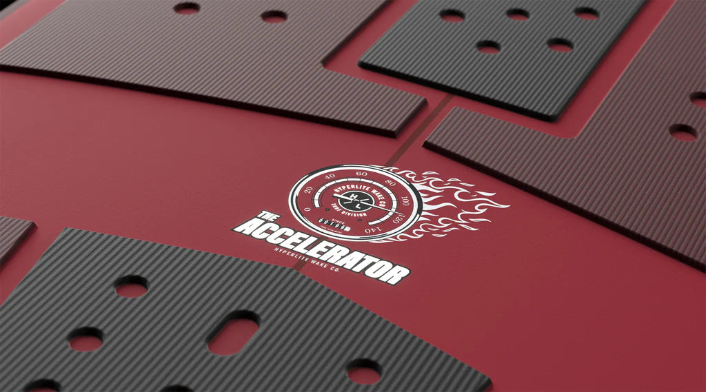 Several textured black plates with cut-out holes are arranged on a red surface featuring the Hyperlite logo, perfect for high-performance setups with the Hyperlite Accelerator Wakesurf Board 2026.