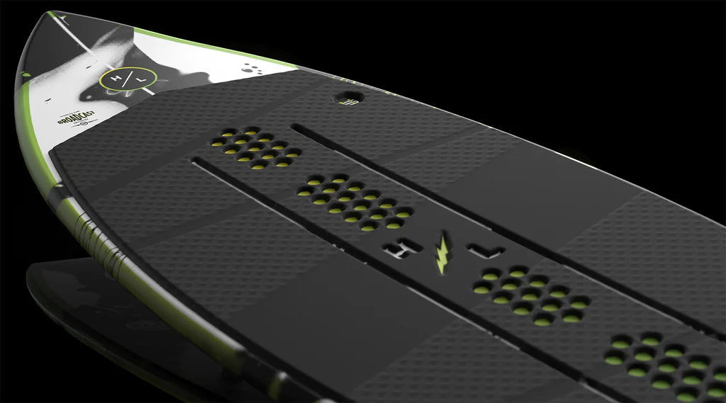 Close-up of the Hyperlite Broadcast Wakesurf Board 2026 by Hyperlite, showcasing its black and green design, textured grip pads, perforated details, and dual concave base, set against a dark background.