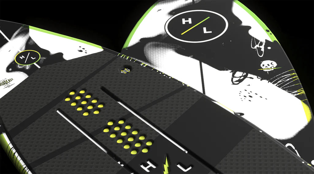 Close-up of two Hyperlite Broadcast Wakesurf Boards 2026 in black and white with yellow accents, bold patterns, textured grips, the HL logo, and a unique hybrid design featuring an abstract skull graphic and dual concave base.