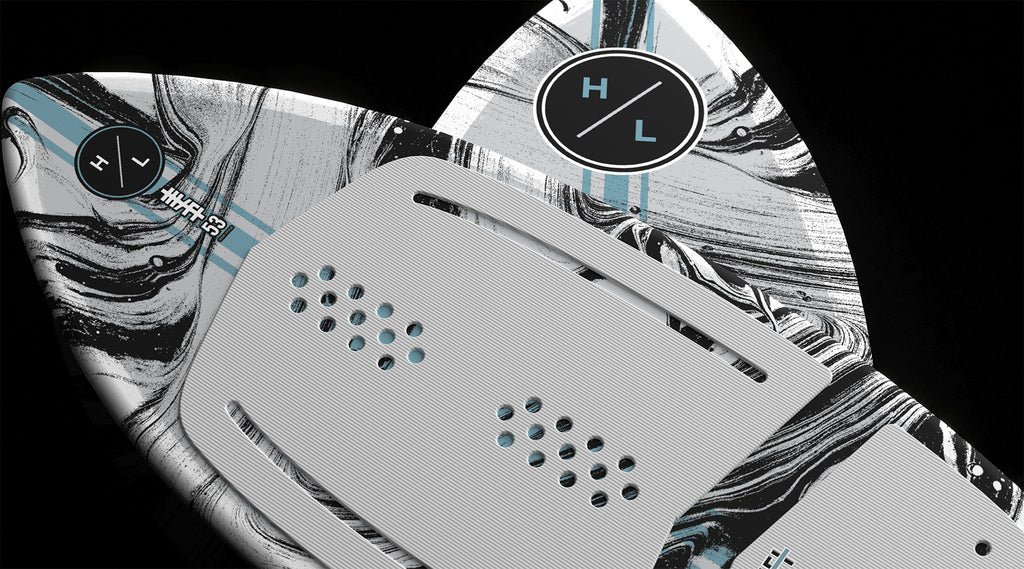 Close-up of the Hyperlite Hi-Fi Wakesurf Board 2026, showcasing black, white, and gray marbled DuraShell, circular Hyperlite logos, and a textured gray EVA traction pad with perforations. Solid black background.