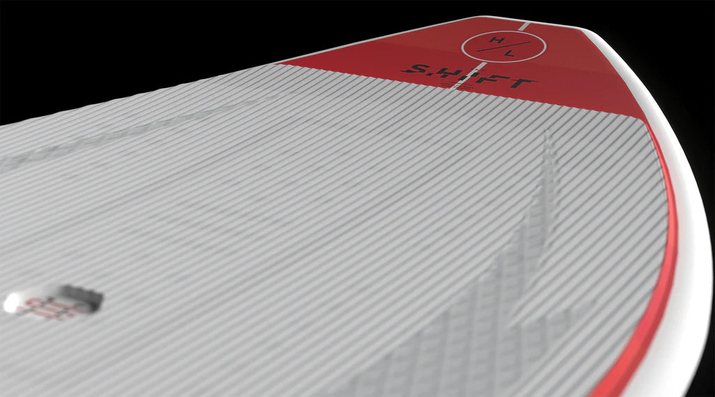 Close-up of the Hyperlite Shift Wakesurf Board 2026, a Hyperlite skim-style board featuring red accents, "SHIFT" branding, and a circular "H/L" logo near the tip, shown against a black background.