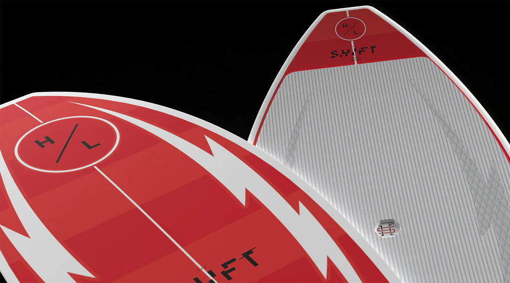 Close-up of two Hyperlite Shift Wakesurf Board 2026 models, red and white with bold angular designs, H/L in a circle near the nose, SHIFT printed on the deck, and an epoxy EPS core for top performance.