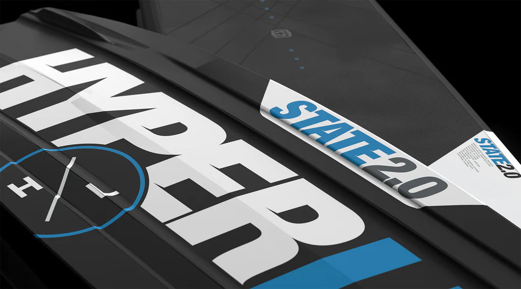 Close-up of the Hyperlite State 2.0 Wakeboard 2026 by Hyperlite featuring bold branding, blue STATE 2.0 edge label, and an asymmetrical design with sharp graphic lines for improved toe-side wake jumps.