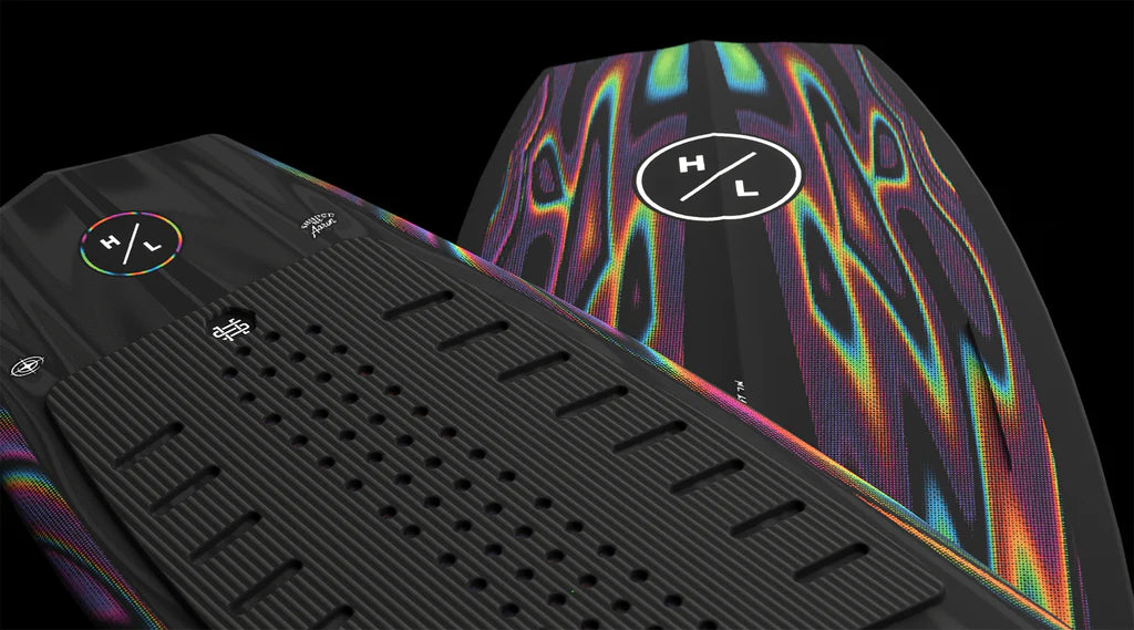 Close-up of two Hyperlite Time Machine Wakesurf Board 2026s with textured black surfaces and vibrant iridescent patterns, highlighted by a white circular H/L logo—an ideal choice for wake surfers seeking a surf style board.