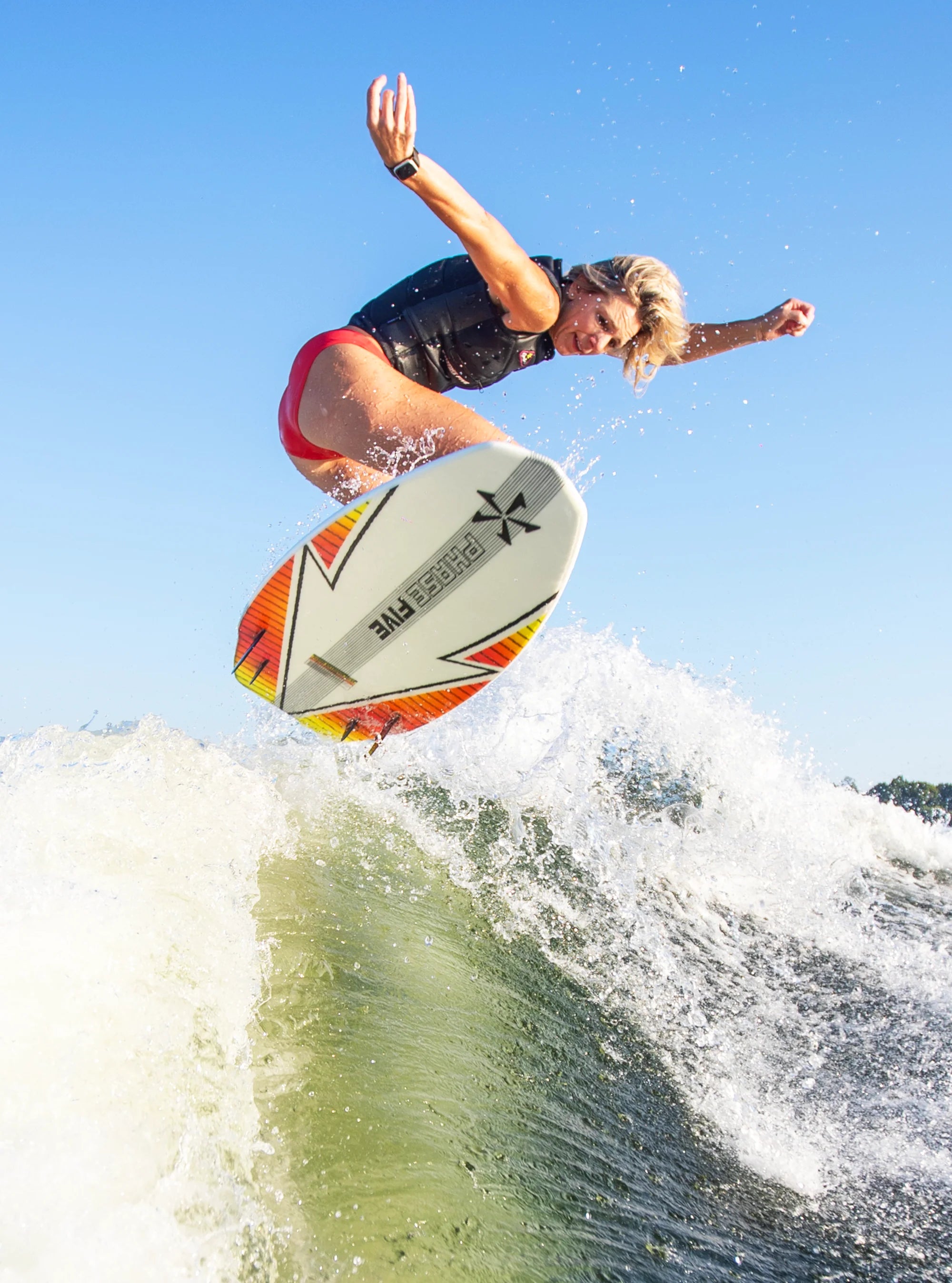 Stacia Bank performs an air on the wake riding her Phase5 2025 Swell Wakesurf Board