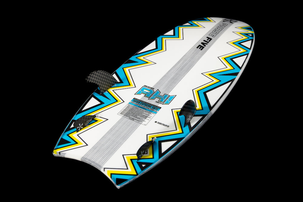 The Phase 5 Ahi Wakesurf Board 2026 features bold zigzag patterns in yellow, black, and turquoise, three black fins, and the letters RH1 near the center, all set against a sleek black background.