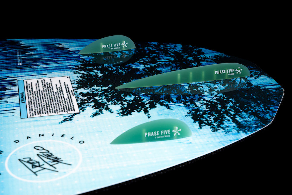 Close-up of the Phase 5 Diamond Turbo Wakesurf Board 2026, featuring blue and black graphics with three green fins and the Phase 5 logo, set against a dark background.