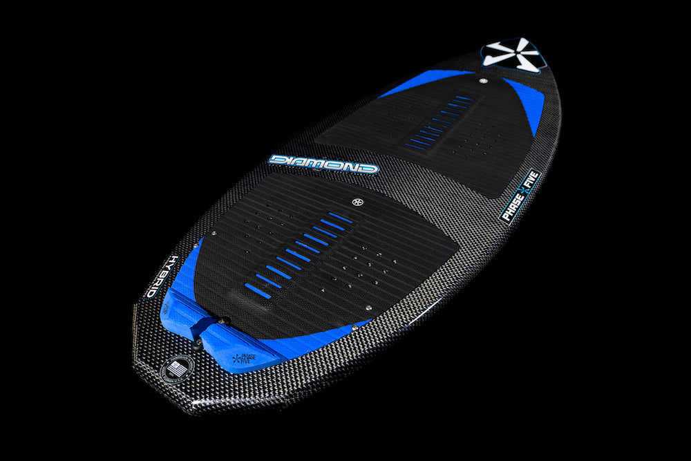 The Phase 5 Diamond Turbo Wakesurf Board 2026 is a black and blue hybrid carbon board with textured grip pads, diamond pattern detailing, and a pointed nose from Phase 5, shown on a solid black background.
