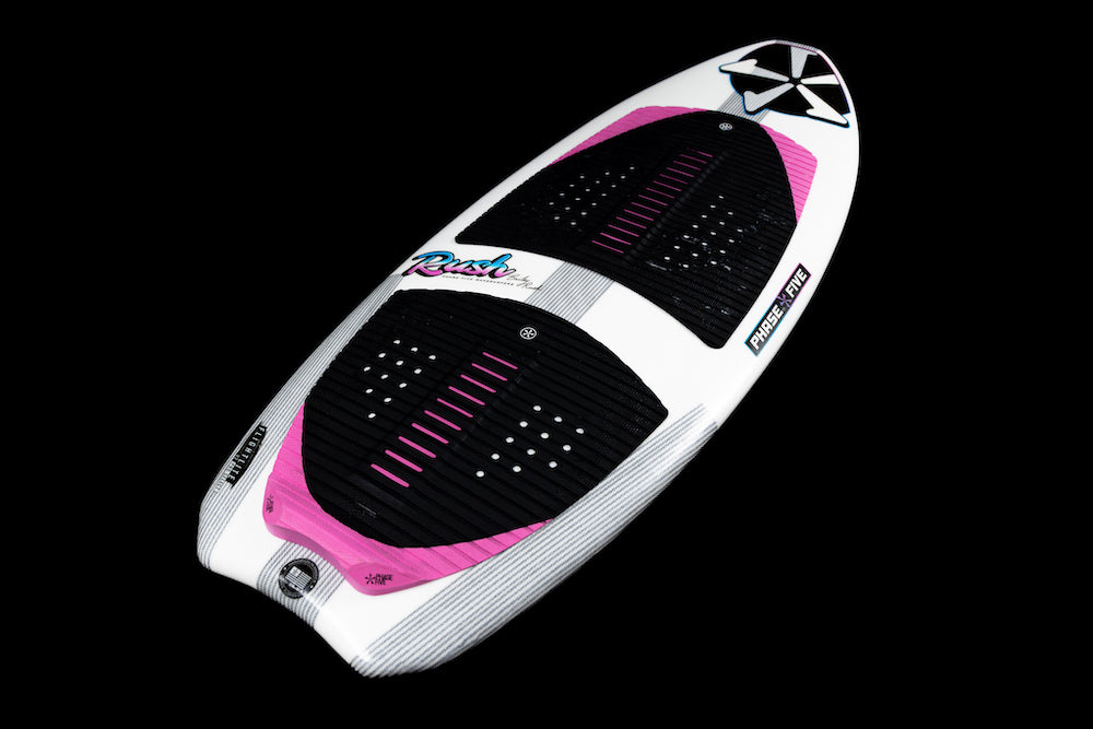 The Phase 5 Rush Wakesurf Board 2026 by Phase 5 is a lightweight performance board with bold blue and pink graphics, black and pink traction pads, black side strips, and is shown on a black background.