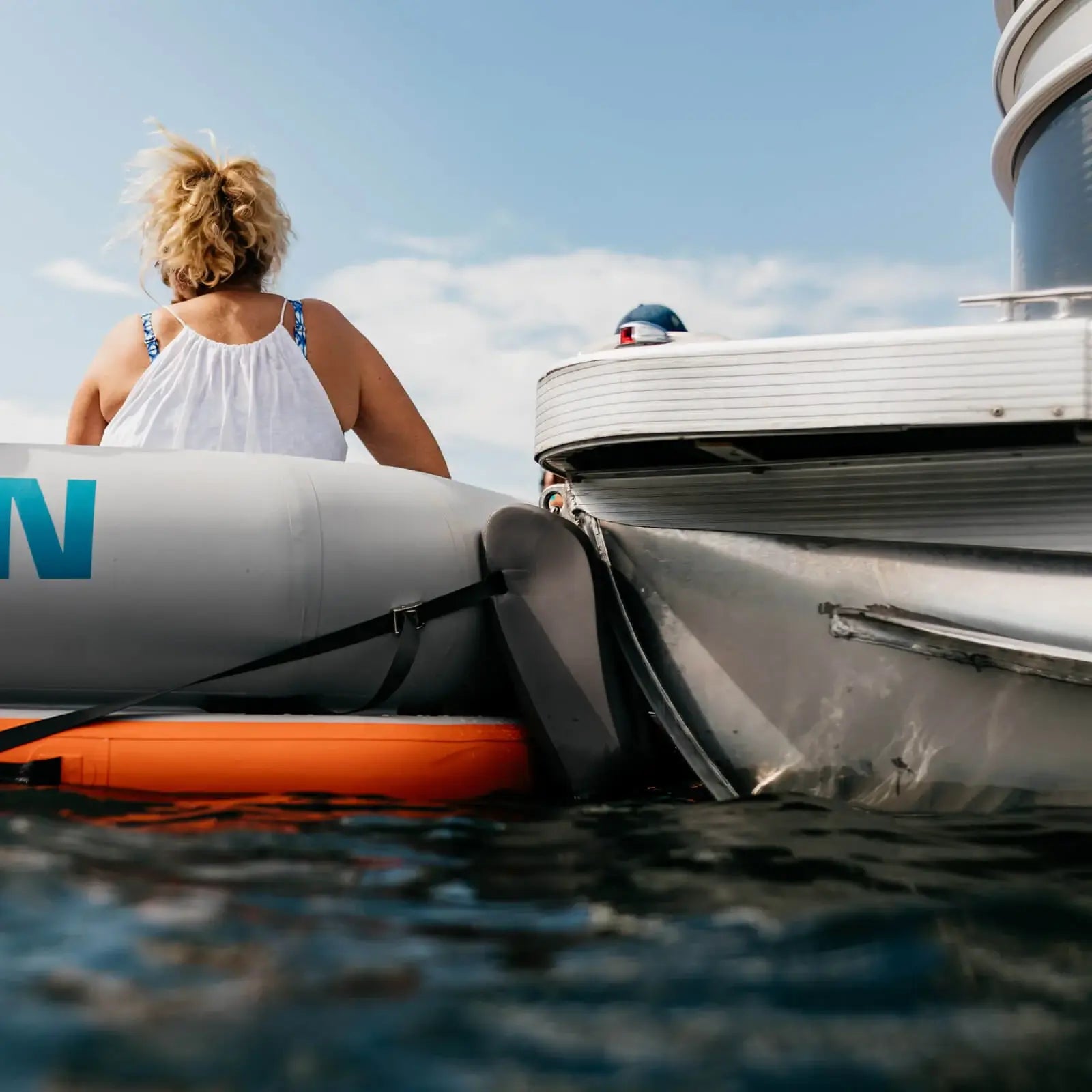 A woman lounges on a MISSION Reef Deck | Inflatable Swim Platform + Lounger in the water.