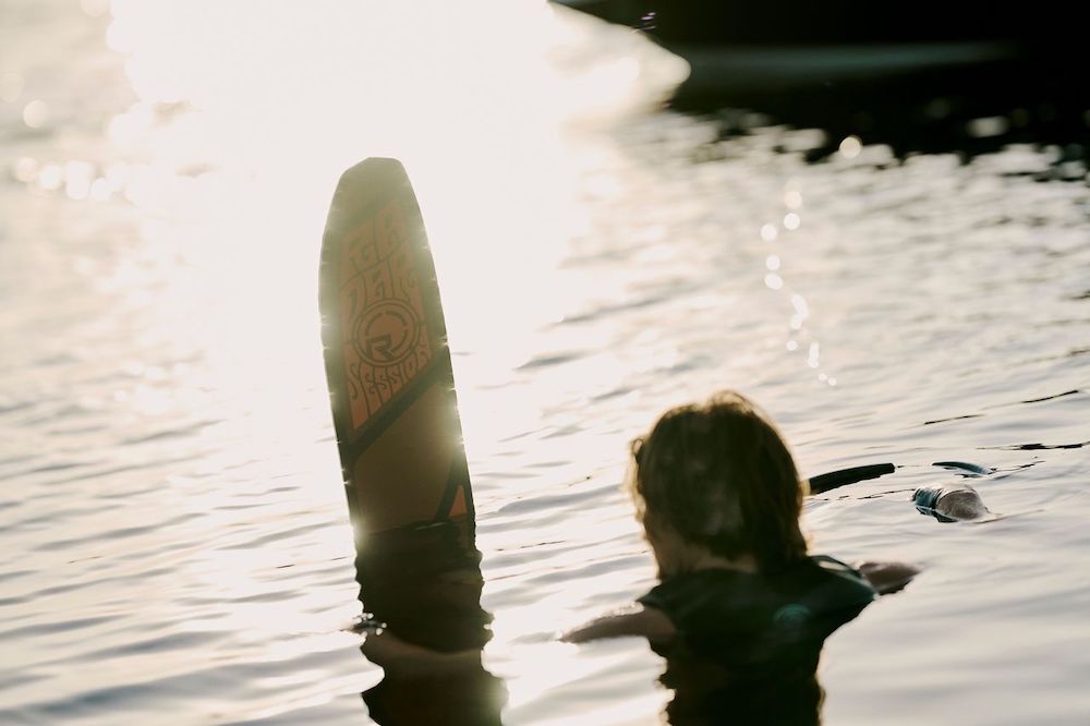 A person floats in water holding the Radar Session Waterski | Prime + ARTP 2026 upright, sunlight dancing on the lake as they embrace the excitement of a Radar adventure.