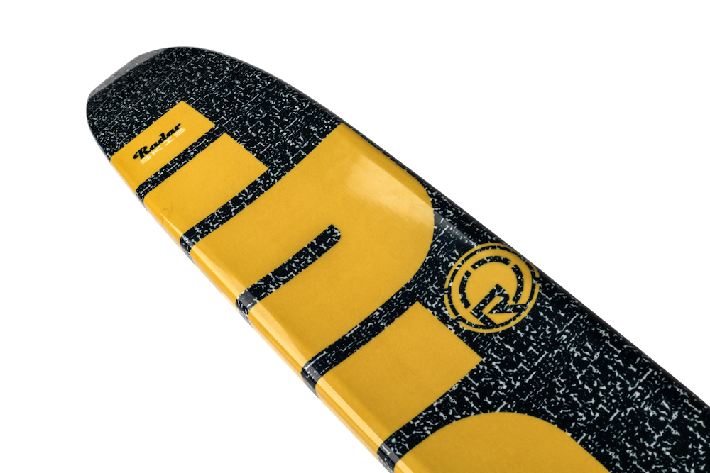 Close-up of a waterski tip with a black and white speckled pattern and large yellow lettering. The Radar brand name appears near the tip, similar to the bold graphics on the 2026 Radar Union Waterski | Prime + ARTP model.