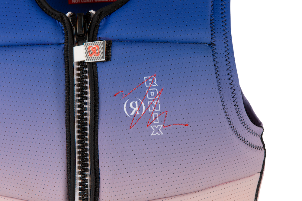 Close-up of the Ronix 2025 Coral Women's CE Impact Vest, showcasing a stylish purple and pink design with a black zipper and embroidered text. The Manhattan tailored fit provides maximum comfort, while the flex foam enhances buoyancy for added safety.