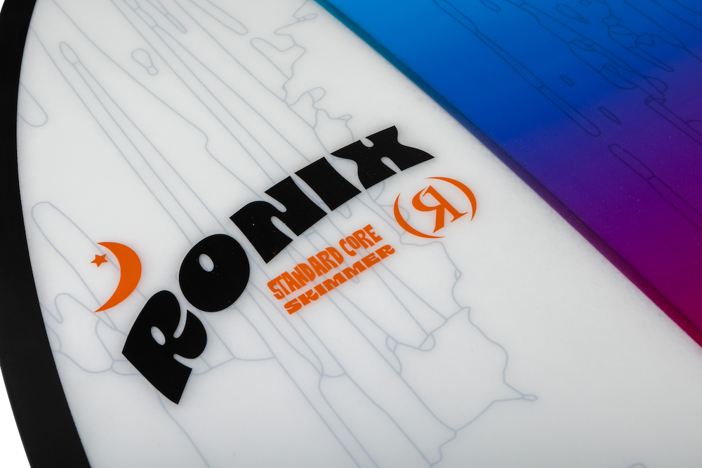 Close-up of the Ronix Standard Core Skimmer 2026—a beginner-intermediate wakesurf board. "RONIX" is in bold black, "Standard Core Skimmer" in orange, with a blue-to-purple gradient edge, ideal for skim style surfing.