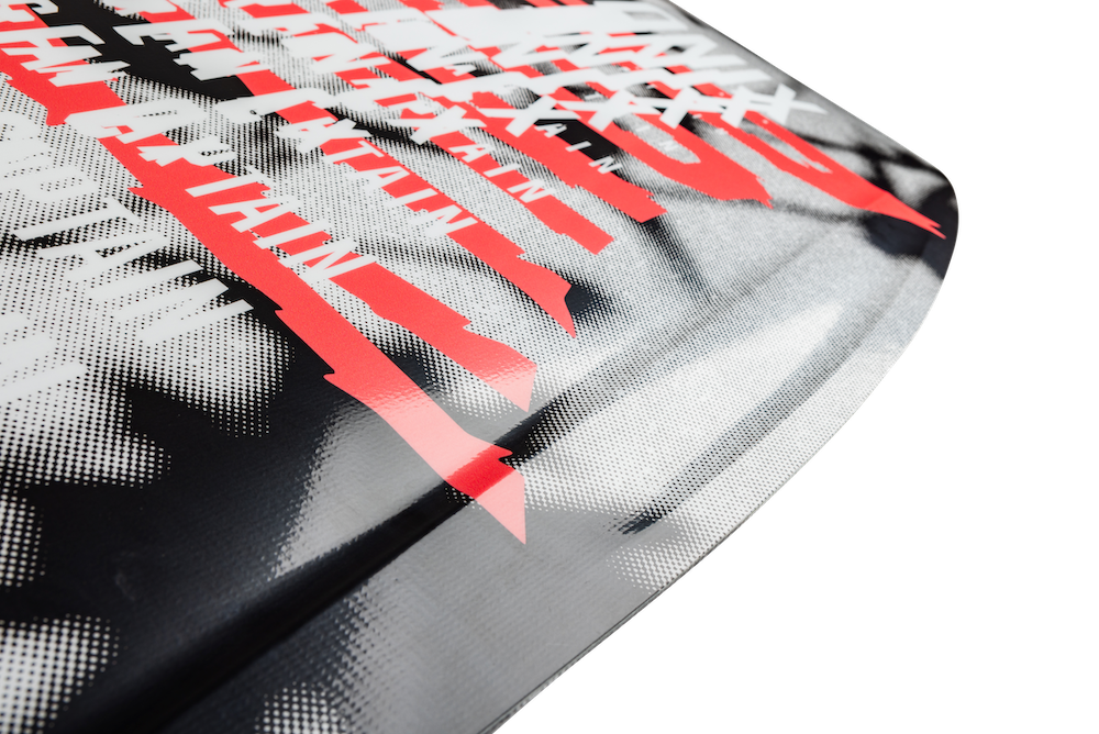 Close-up of the Ronix Women's Sea Captain Wakesurf Board 2026, showcasing dynamic black and white halftone graphics, bold red diagonal lines, and partially hidden white text for a surf-inspired, energetic look.