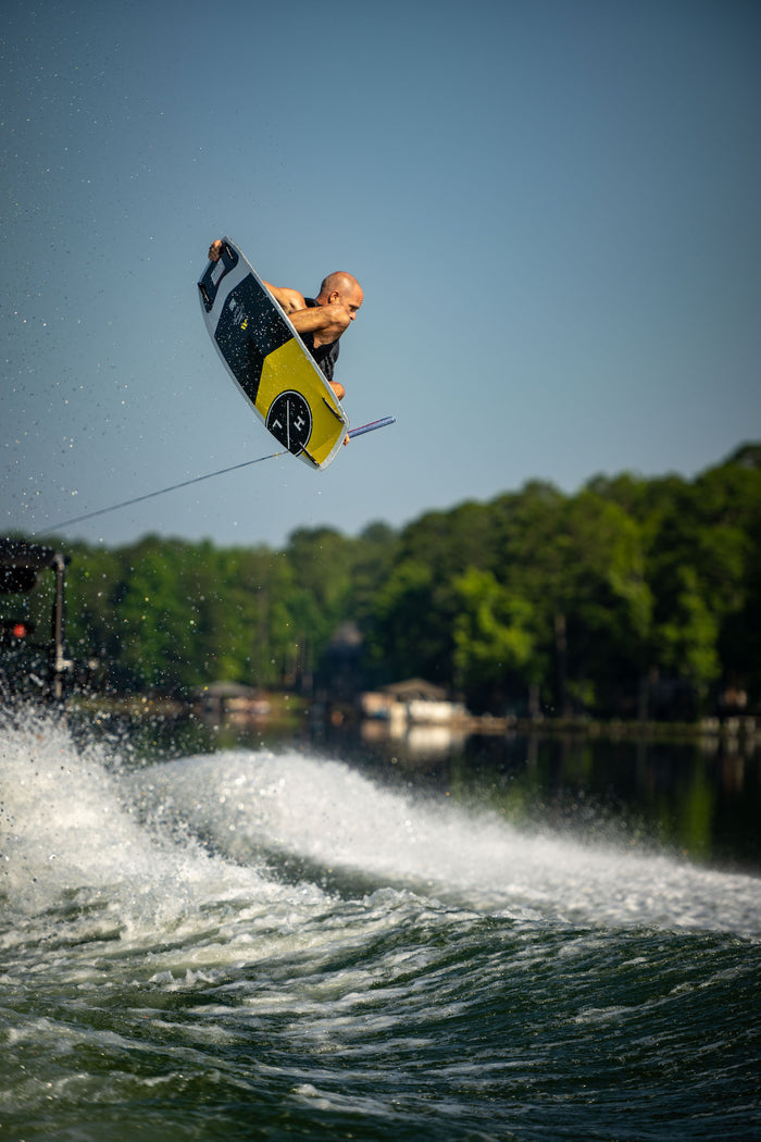 A man is effortlessly gliding through the air on a Hyperlite 2023 Murray Pro wakeboard, equipped with the Team OT bindings - a signature model designed by Shaun Murray.