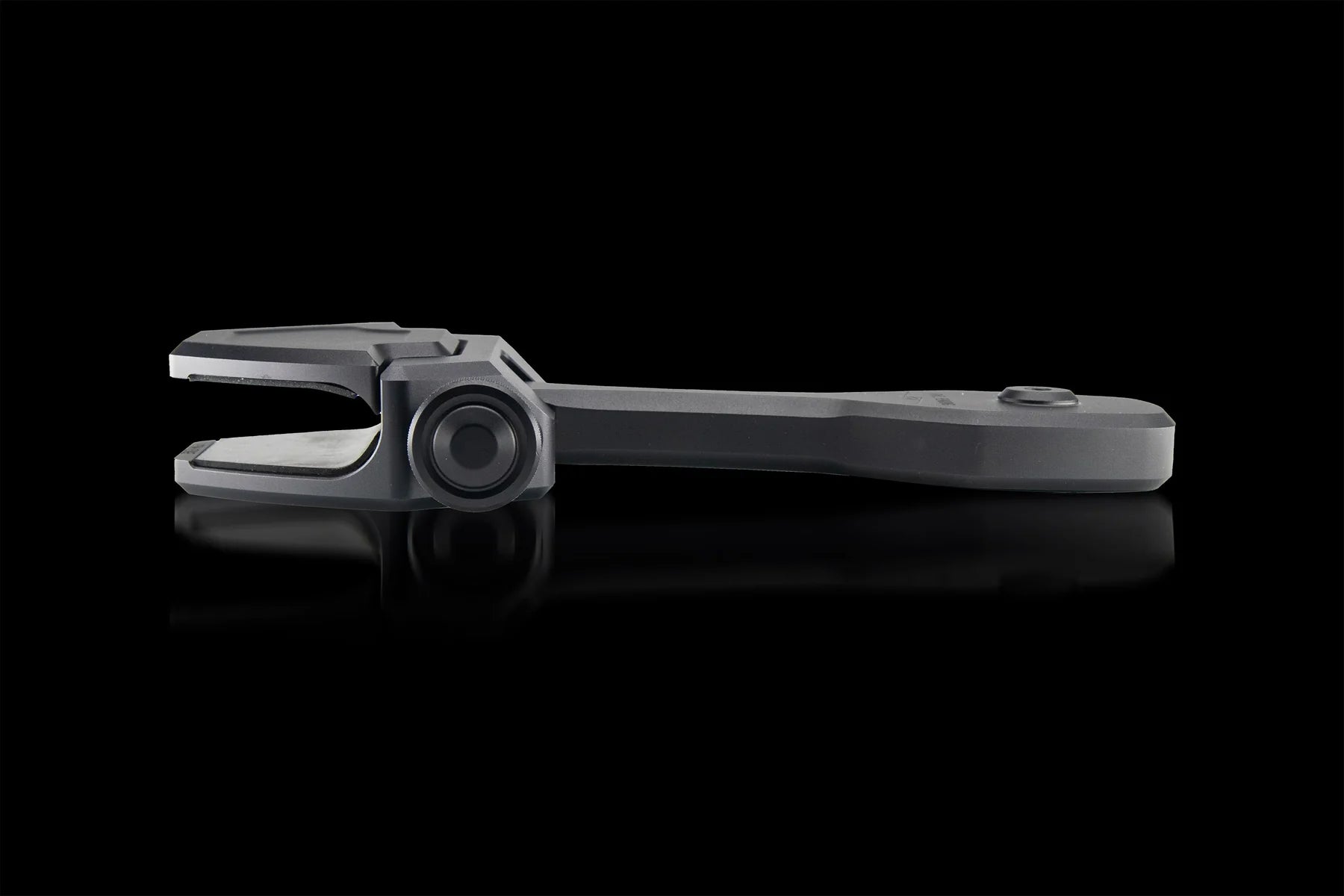 A matte gray adjustable wrench lies flat on a glossy black surface next to a PTM Edge ZXR-320 Windshield Mounted Pivoting Mirror Bracket, both positioned horizontally with subtle reflections on the black background.