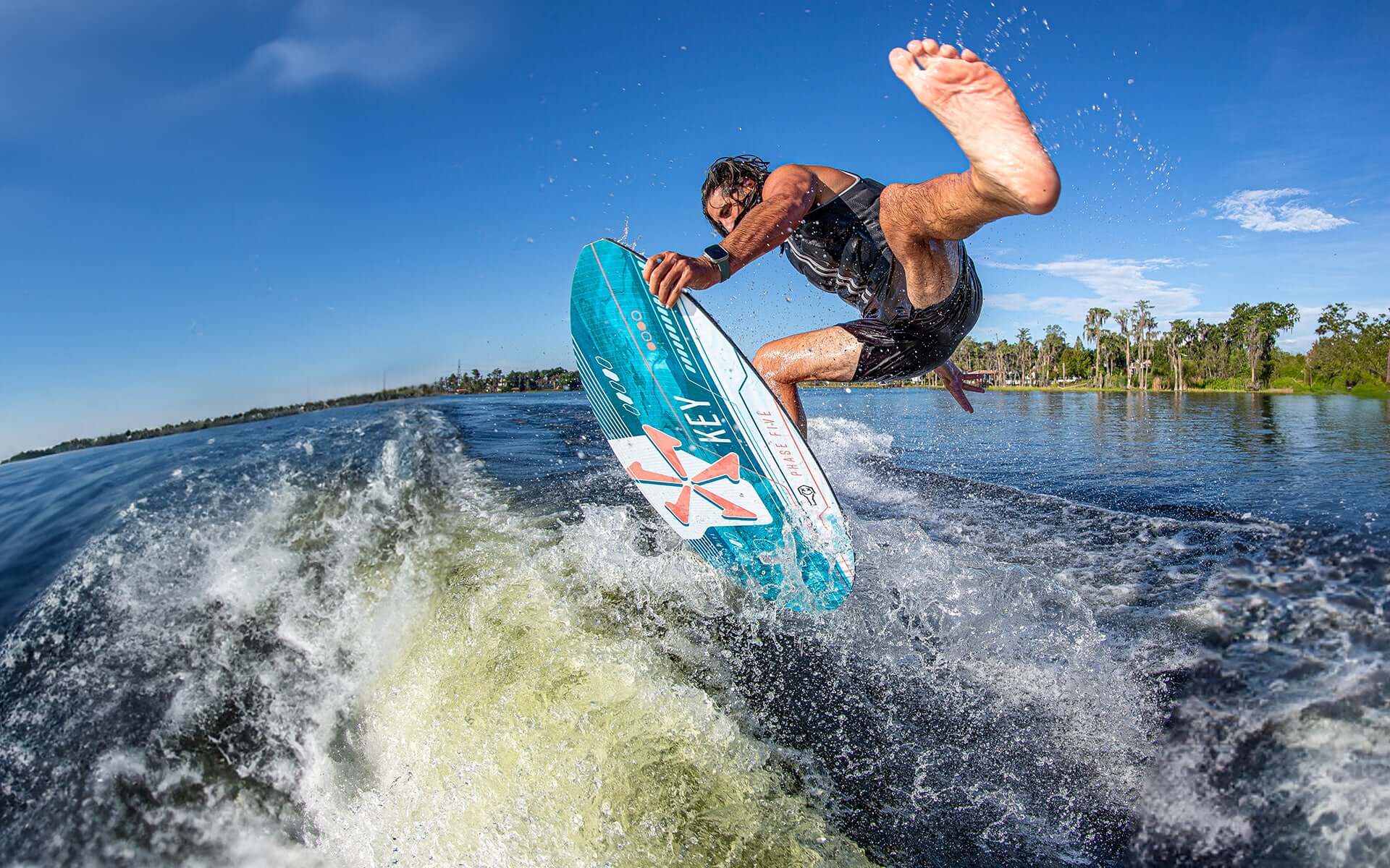 An advanced wakesurfer is riding a Phase 5 2024 Key Wakesurf Board in the water.