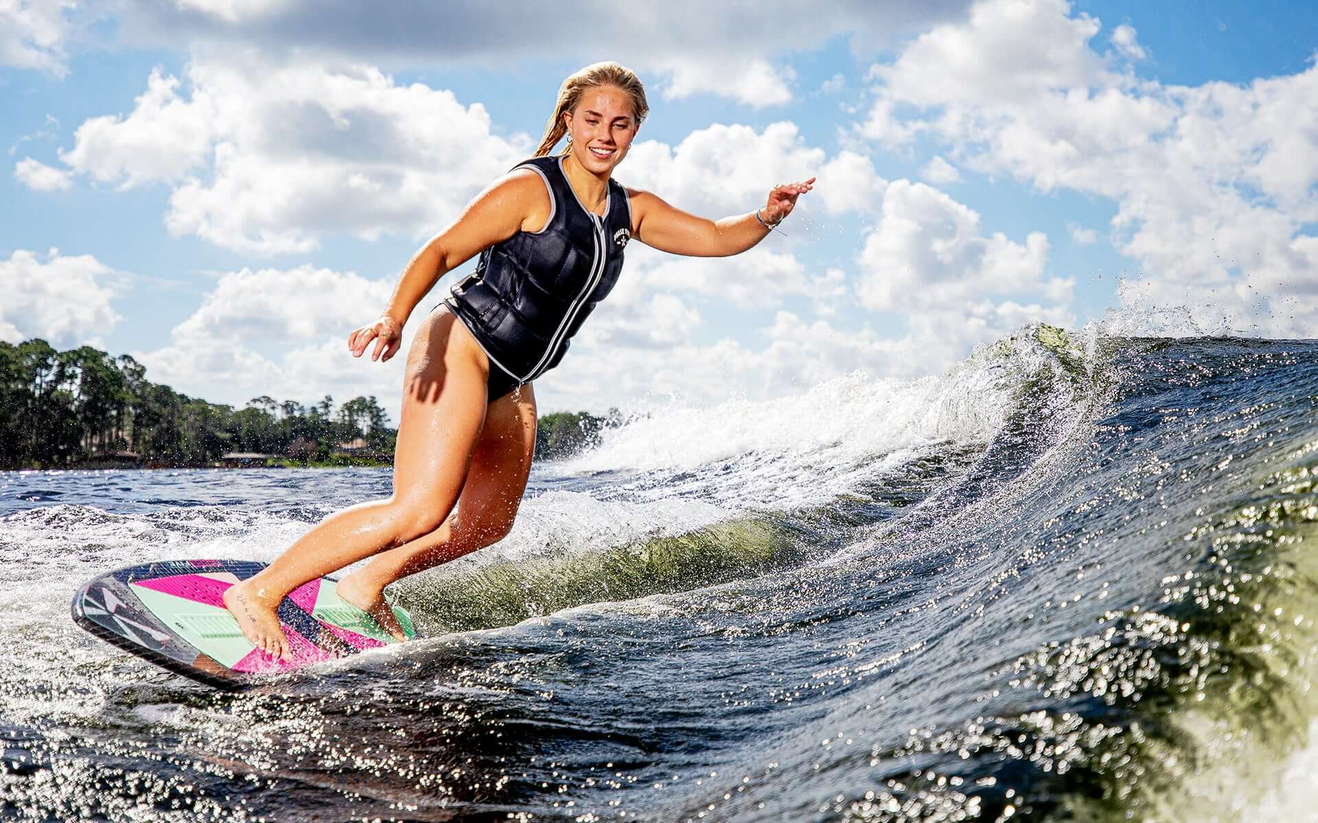 A woman riding a wave on a Phase 5 2024 Diamond Luv Wakesurf Board.