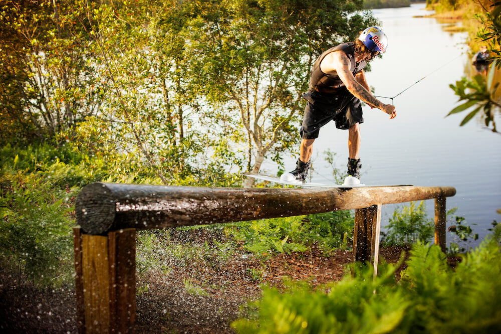 Massi, an avid skateboarder, effortlessly showcases his skills as he gracefully rides his skateboard over a wooden railing. With lightweight flexibility and the precision of Ronix 2024 RXT BOA Boots, he achieves a