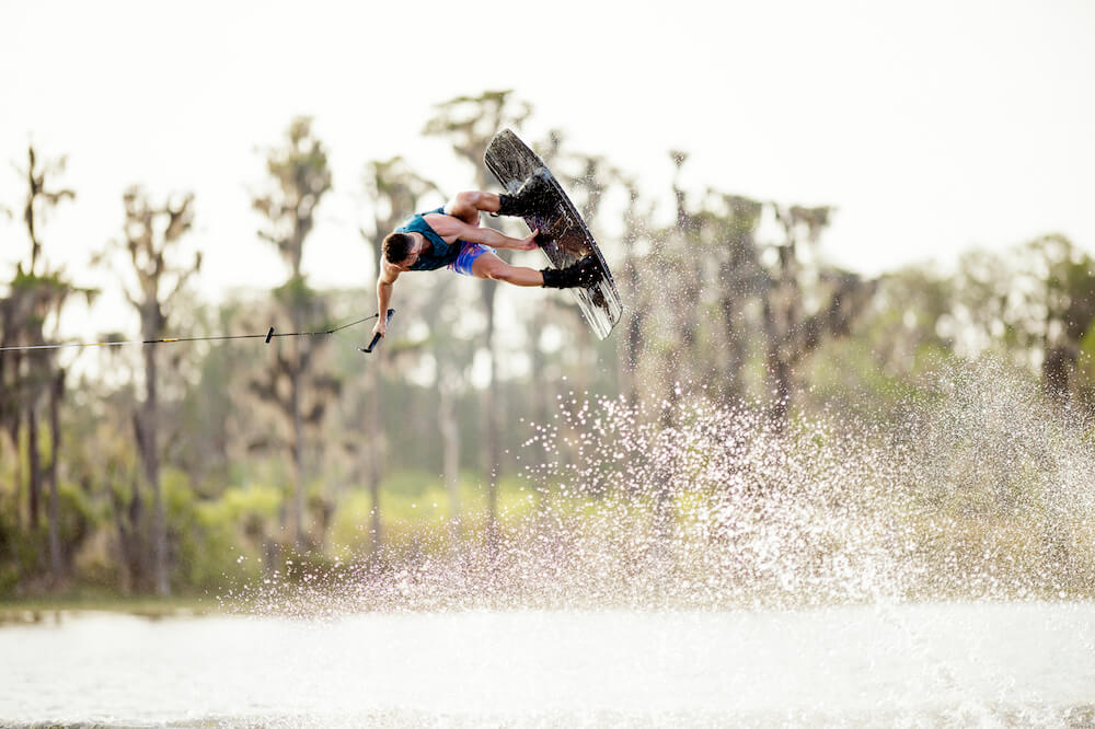 A person performing a high-response trick on a wakeboard using the heat moldable Ronix 2024 One Carbitex Boots.