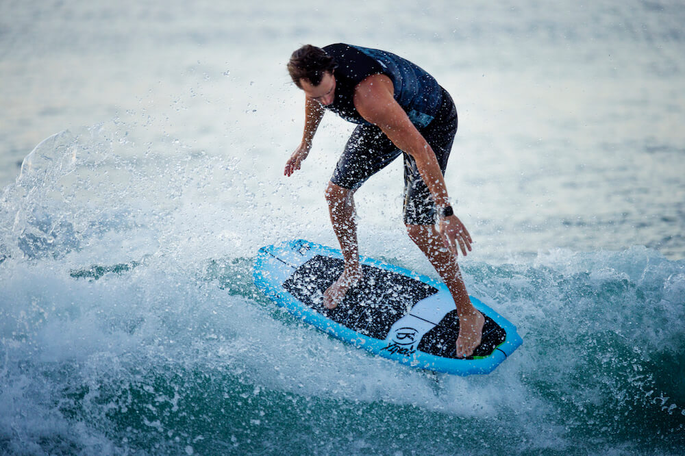 A man riding a Ronix 2024 Flyweight Pro DNA wakesurf board on a wave.