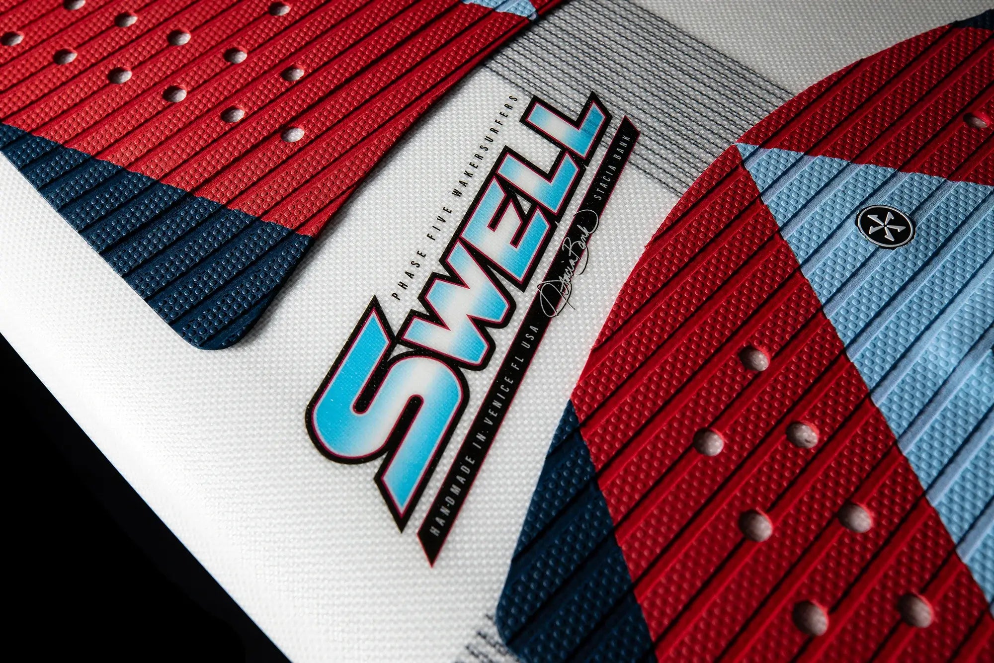 A close up of a Phase 5 Swell Wakesurf Board with a red, blue and white design.