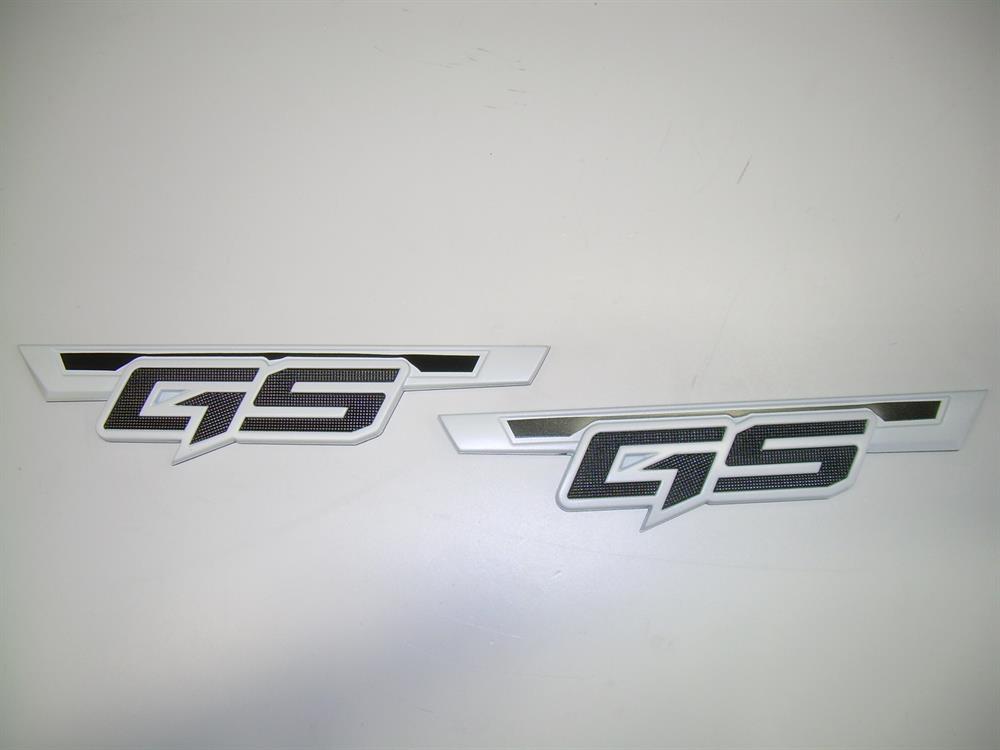 The Nautique DECAL GS20/22 MODEL DESIGNATOR CHROMAX SET WHITE (170137) features two identical white and black GS badges, perfect for your GS20/22, shown on a plain white surface.