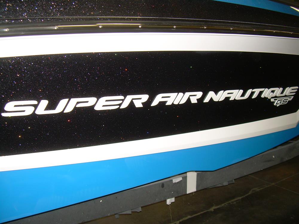 Close-up of a Nautique DECAL SUPER AIR NAUTIQUE CHROMAX WHITE CHROME 2.55 X 69 - 170289 from Nautique, shown on the side of a boat with a sleek black and blue background.