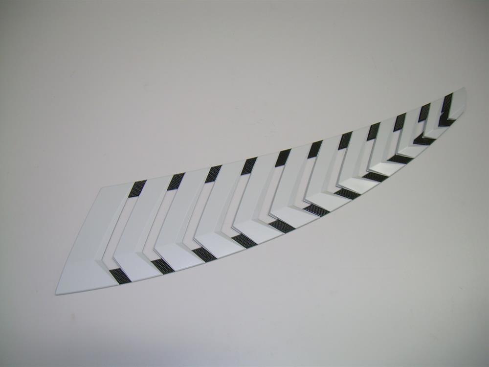 A Nautique DECAL G SERIES VENT starboard WHITE CHROMAX 8 X 27.75 - 170301, featuring a white curved design with alternating black and white rectangles like piano keys, sits on a light surface. Brand: Nautique.
