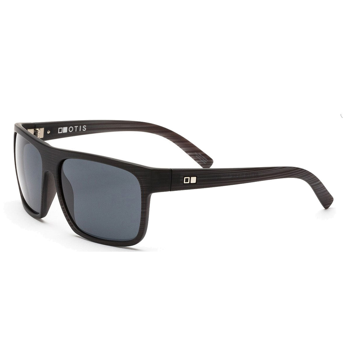 The Otis After Dark - Black Woodland Matte/Grey Polar sunglasses feature square black frames with a wood grain texture, grey mineral glass lenses offering 100% UVA/UVB protection, and the OTIS logo on the inner arm.