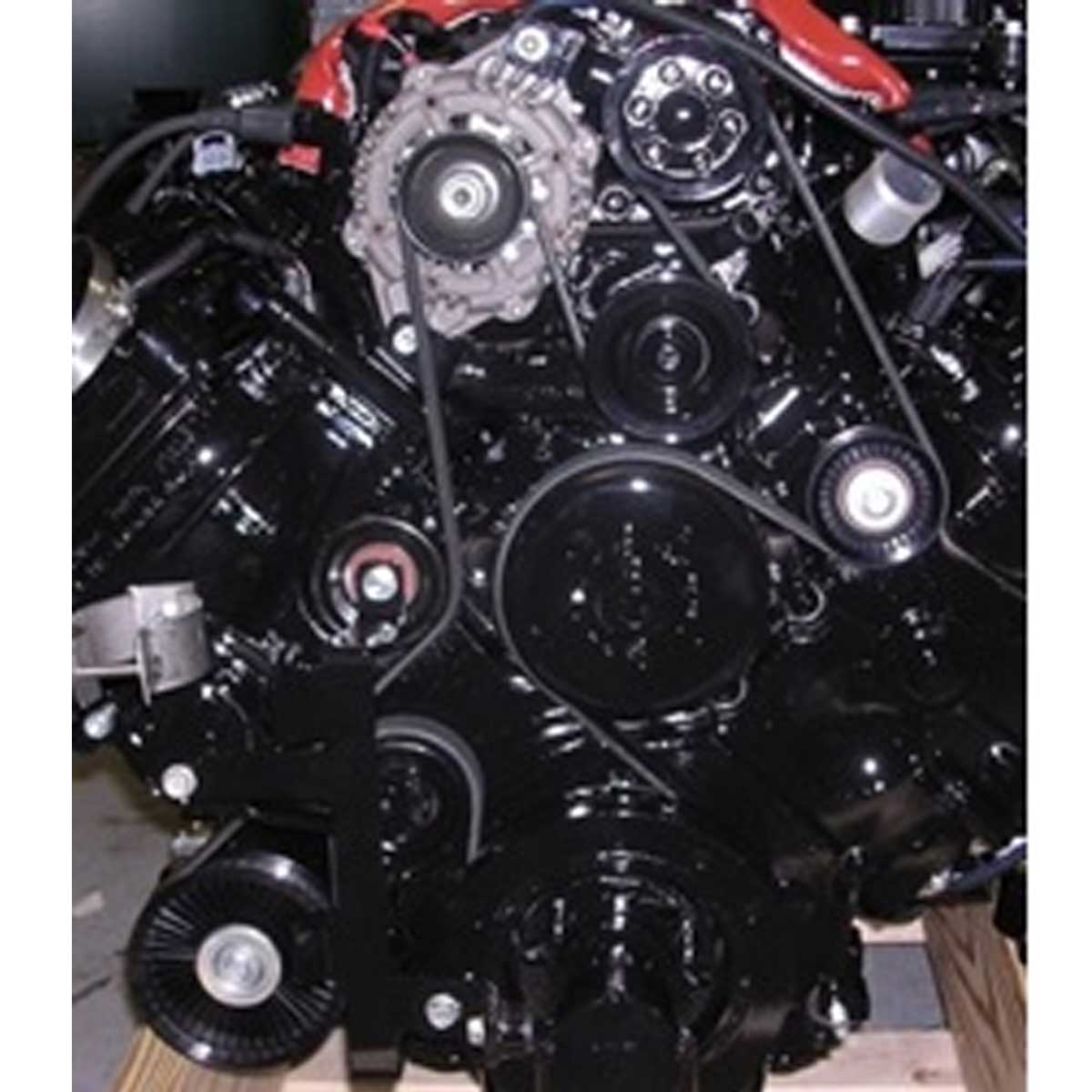 Close-up of an Indmar Belt 6.2L Ford Supercharged 95 Amp Alt (725902) engine by Indmar, black with multiple pulleys and visible mechanical parts, resting on a wooden pallet in a workshop or garage.