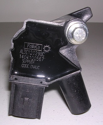 A close-up of the Indmar COIL FORD 6.2 BANK 2 - 597032 ignition coil, branded by Indmar with part numbers, on a gray surface—ideal for replacing engine bank 2 coils.