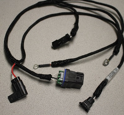 An Indmar HARNESS 6.2L FORD INTERCOOLER 575 2017 (805913) automotive wiring harness with multiple connectors and ring terminals is displayed on a light gray surface, featuring durable braided sleeving for protection.