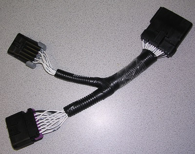 The Indmar ADAPTER 6.2L FORD 24 PIN TO 16 PIN (2017 - 805914) wiring harness features black connectors, bundled wires in protective tubing, and is ideal for use as an Indmar adapter. Shown resting on a light gray surface.