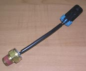 The Indmar SWITCH TRANS TEMP 240 W/LEAD (885191) is a short black cable with a brass connector and a black plastic connector with a blue clip, used for switch trans temp applications.