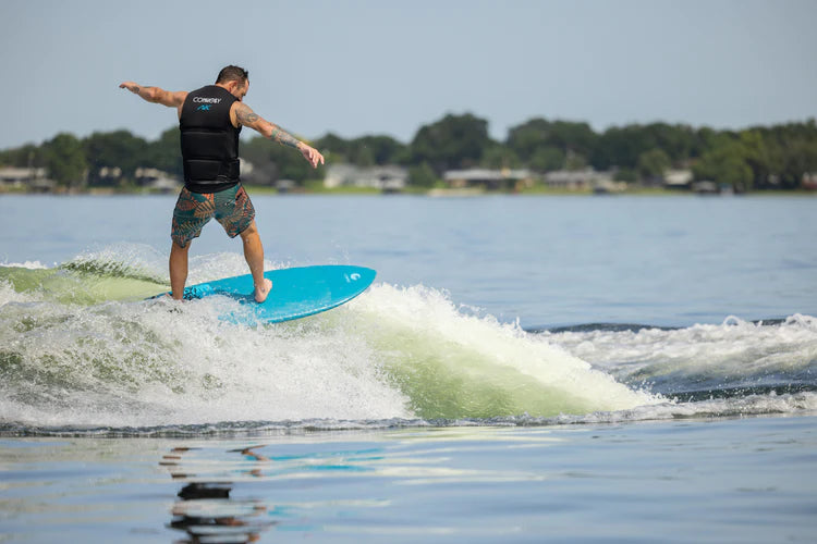 A man showcasing his surf style as he expertly maneuvers on a wave, riding it with unparalleled maneuverability on the Connelly 2024 AK Wakesurf Board by Connelly.