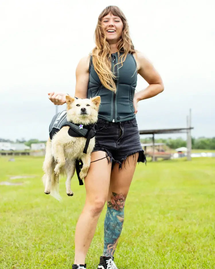 A woman wearing a Follow Wake backpack with a Follow Dog Floating Aid - Black inside, secured with buckle straps.