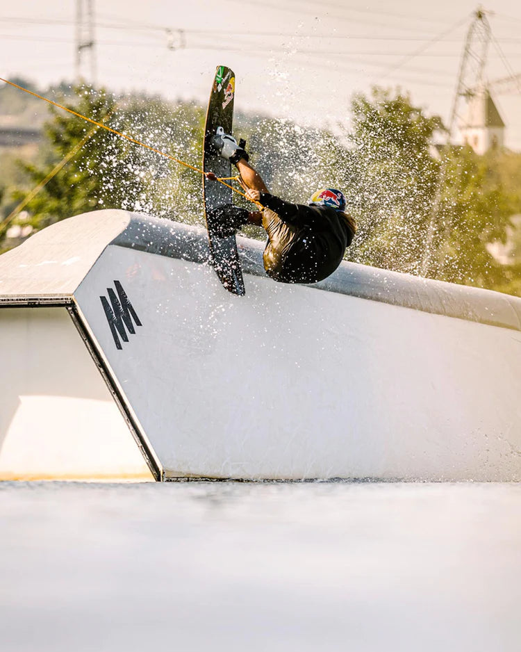 A person doing a trick on a snowboard, showcasing their skills and braving the wind chill factor while wearing Follow Wake neoprene jackets with Aquaguard® Stash pockets.