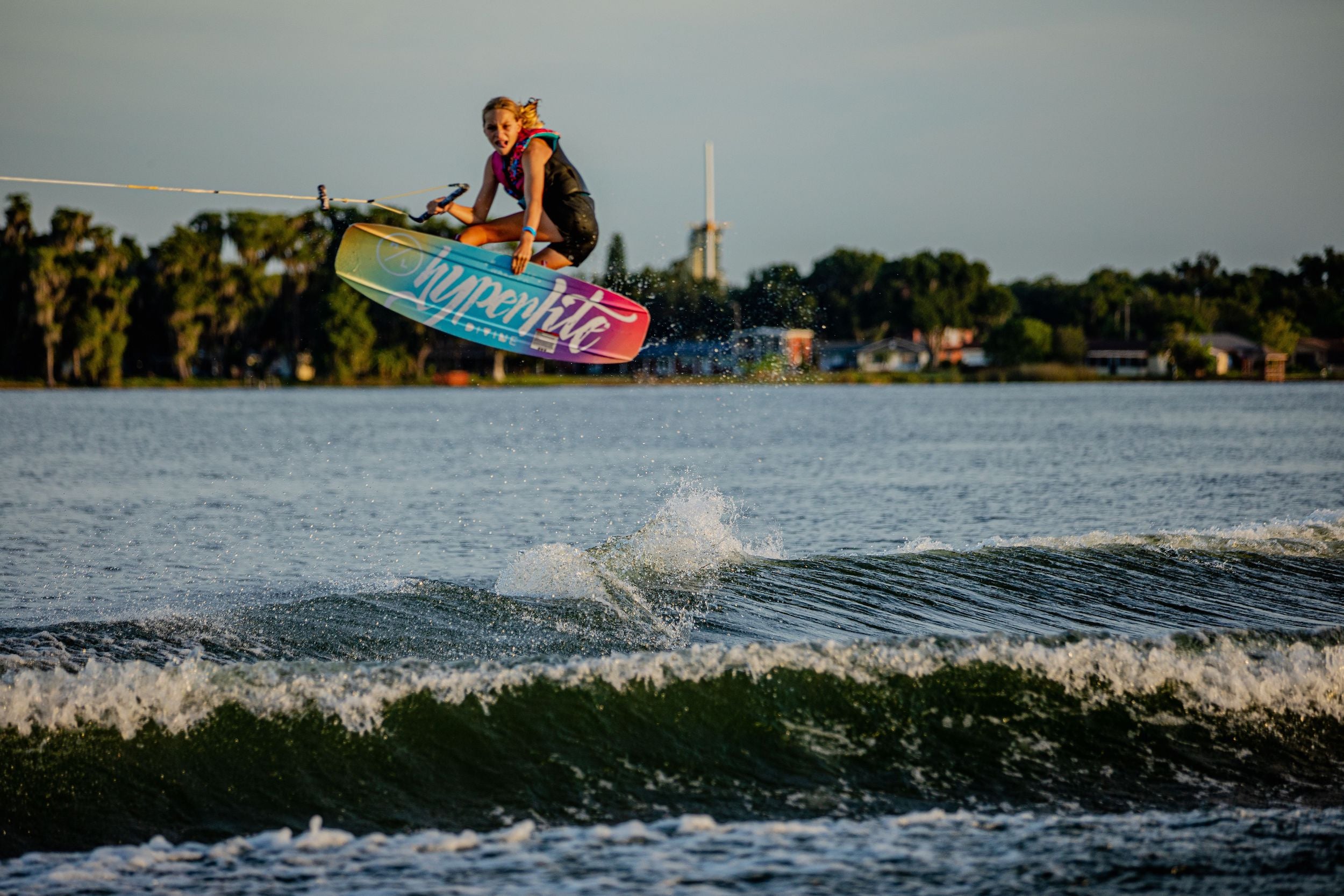 A beginner/intermediate rider enjoying the Hyperlite 2024 Divine Jr. Wakeboard in a lake.