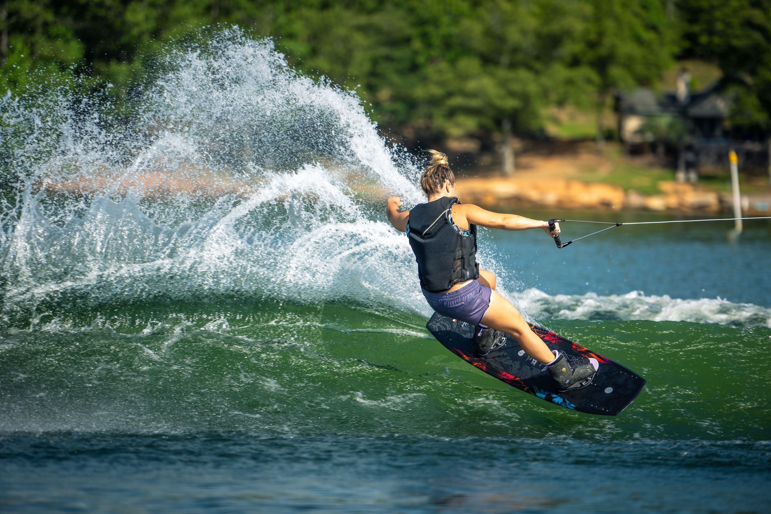 A woman is riding a Hyperlite 2023 Venice Wakeboard on a Venice lake.