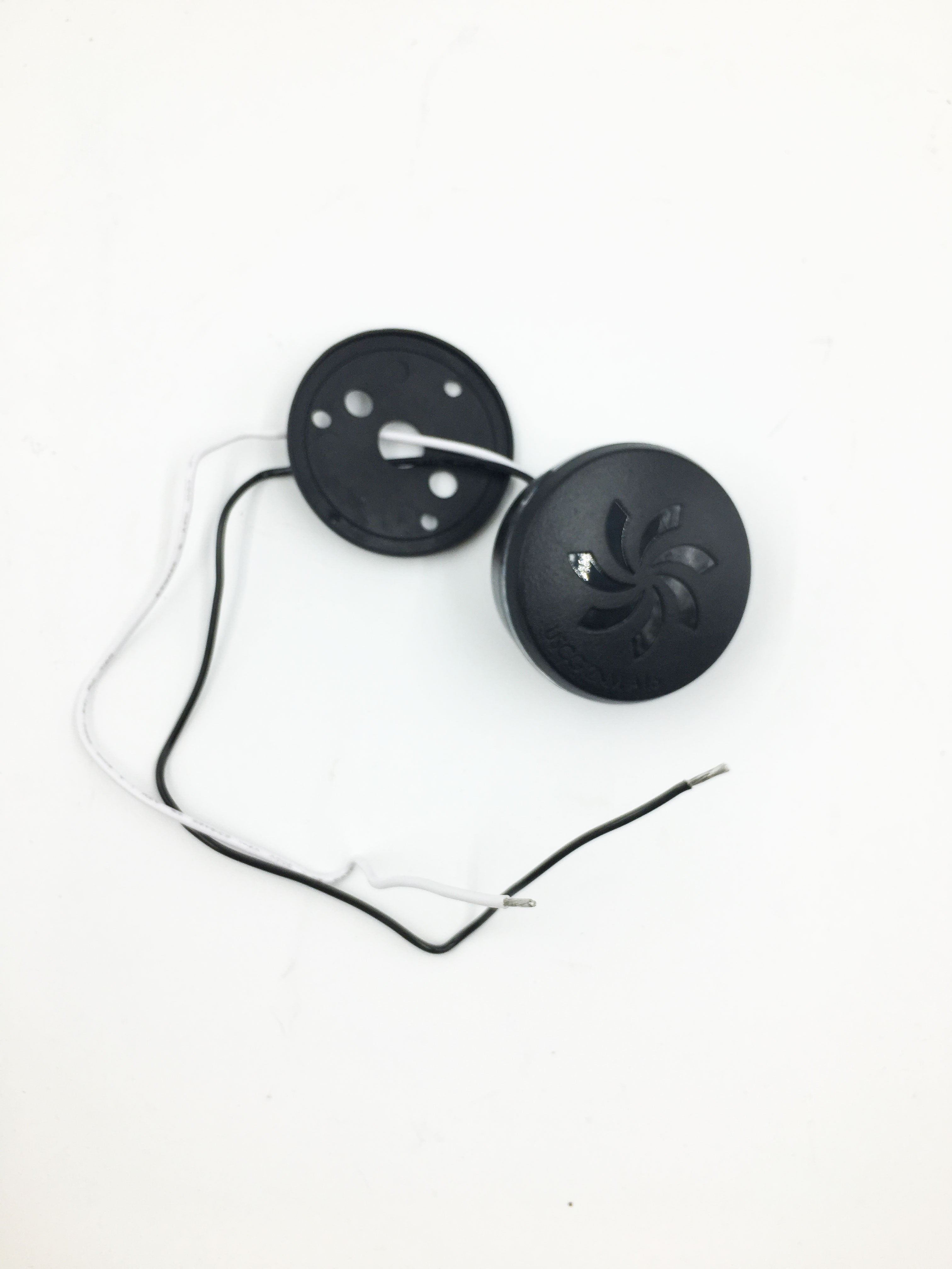 Two small black electronic components from the Malibu Tower 2V LED All-Round Navigation White Light (4121014) are connected by black and white wires. One cover has ventilation slots, the other holes; stripped wires sit on a white background.