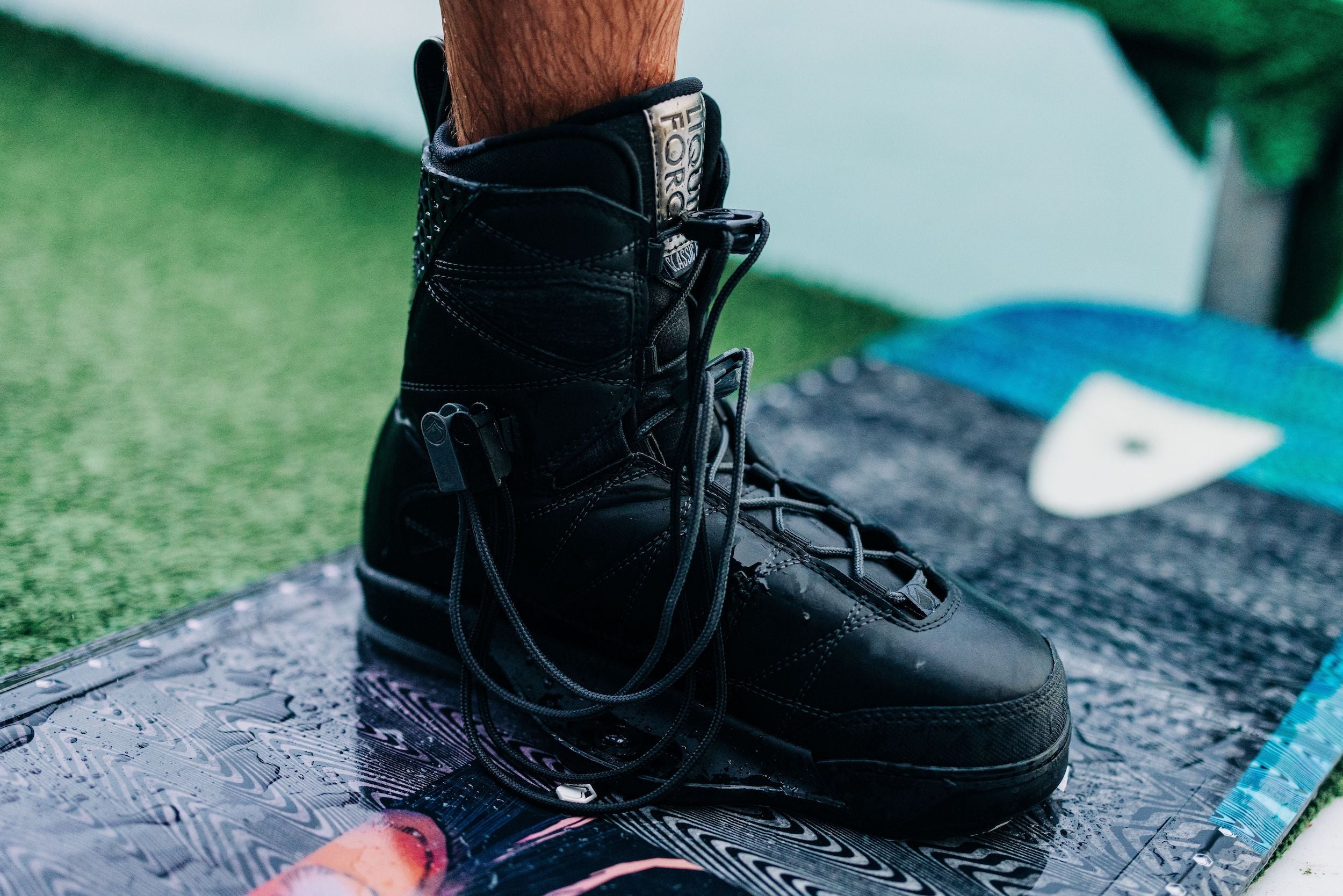 A pair of Liquid Force 2024 Classic 6X Boots with a 6X chassis binding on top of a board.